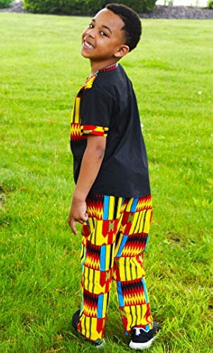 Child smiling in colorful African pattern outfit on grass.