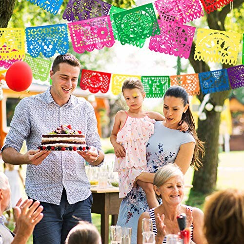 Family celebrating outdoors with cake and colorful decorations.